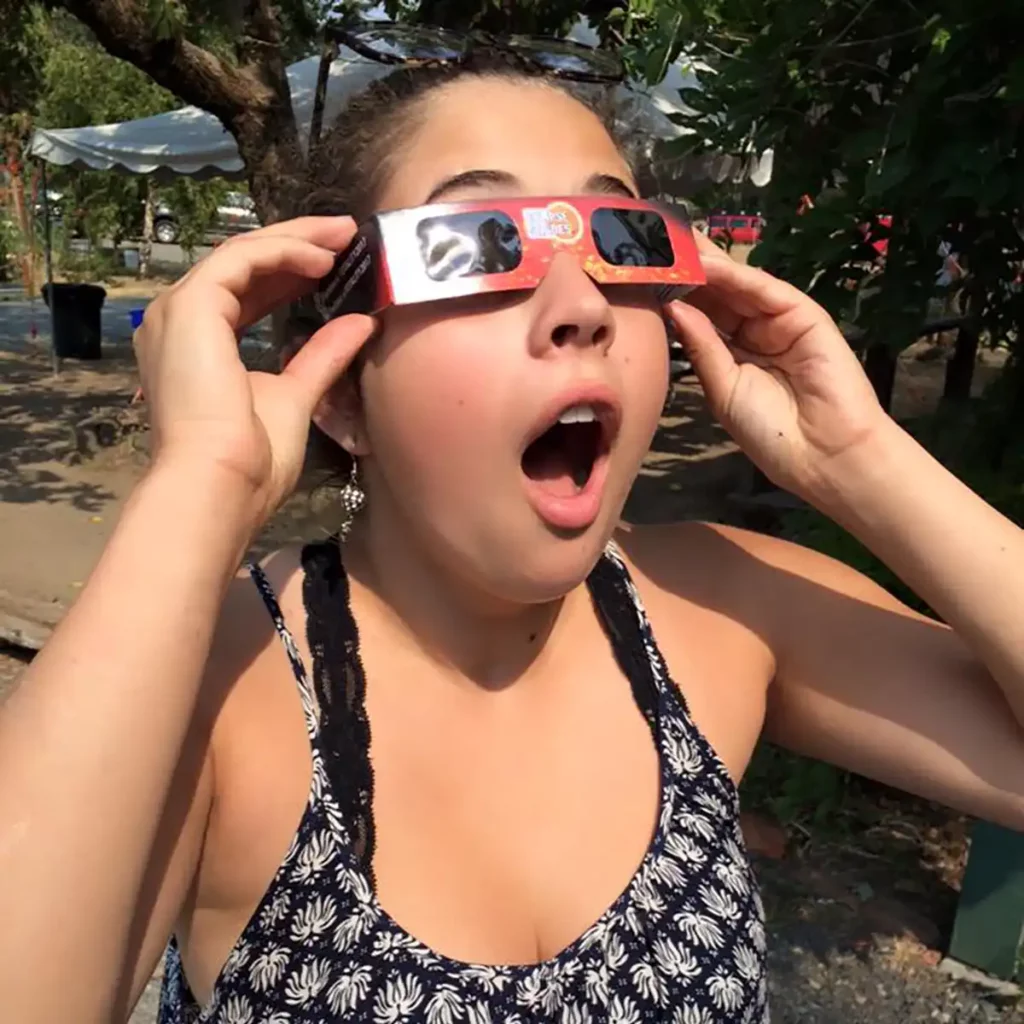 Girl viewing eclipse using protective glasses